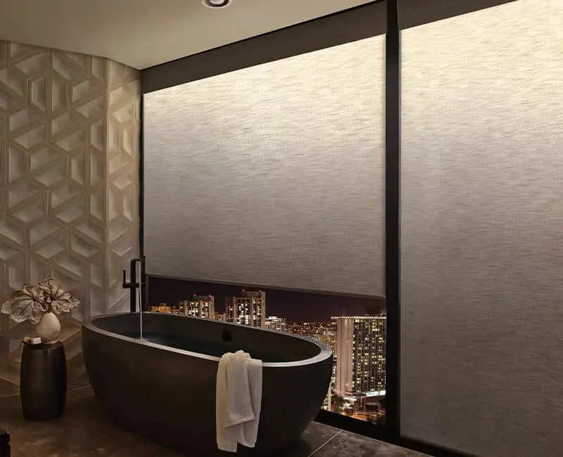 Modern city view bathroom with black freestanding tub, decorative wall, ambient lighting, elegant decor, spacious layout, nighttime cityscape, sophisticated design.