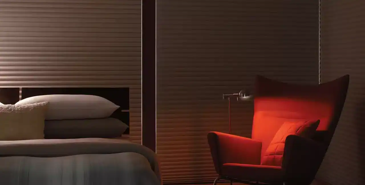 A stylish bedroom featuring a comfortable bed and a cozy, modern reading chair illuminated by a warm red light, perfect for relaxation and leisure.