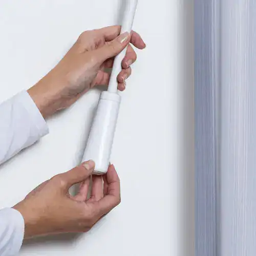 Hands installing the Luminette Powerview automated window shade system for smart home convenience.
