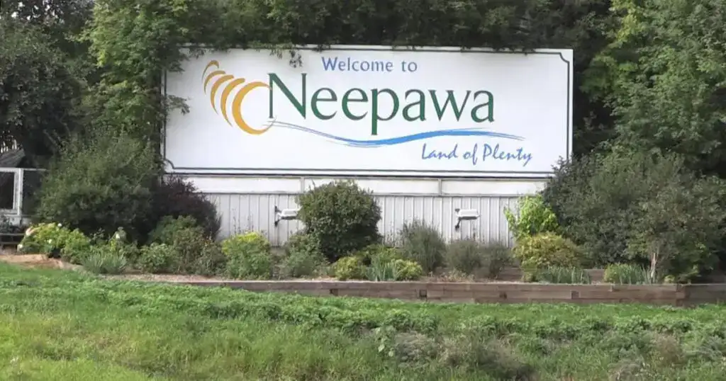 Welcome to Neepawa, MB sign with lush greenery and welcoming message.