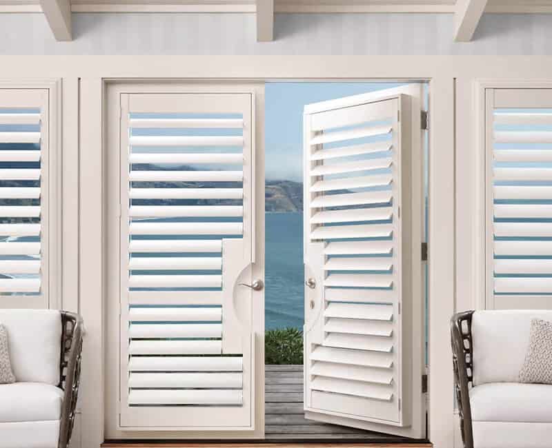 Bright white louvered shutters open to ocean view.