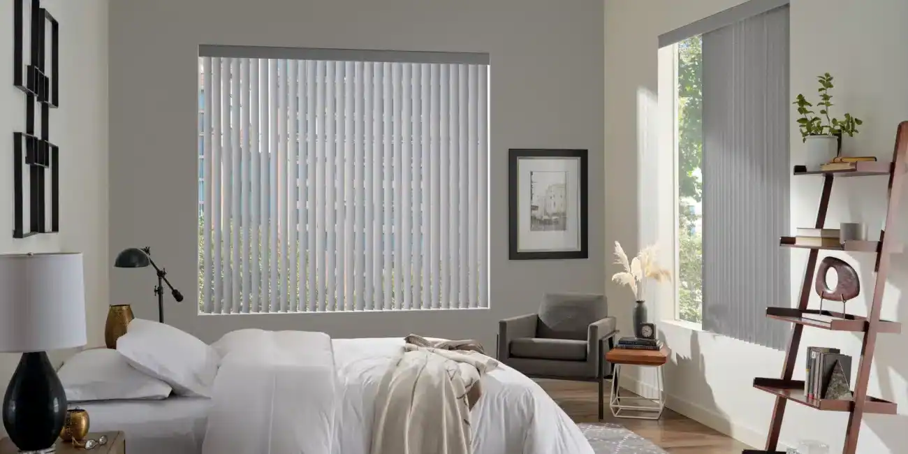 Spacious bedroom with large windows and vertical blinds, soft bedding, modern decor, and natural sunlight, creating a calm, relaxing environment ideal for contemporary living spaces.