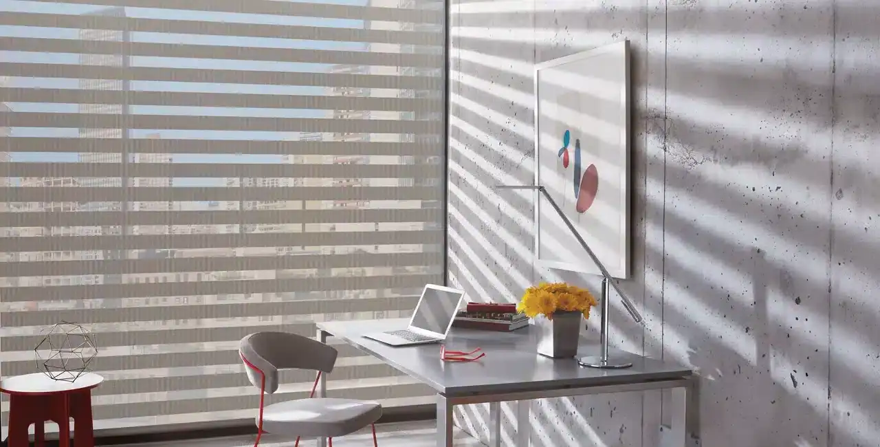 A bright, modern office with a minimalist aesthetic, featuring a sleek desk, laptop, comfortable chair, vibrant flowers, and abstract artwork, illuminated by natural light filtering through stylish horizontal blinds.