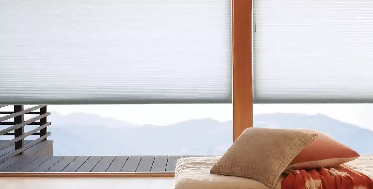 duette cellular shades on a window with pillow next to it