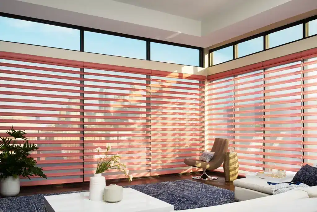 Bright living space with large windows and pink blinds, showcasing modern decor, comfortable seating, and cityscape exposure for a relaxed, contemporary atmosphere.