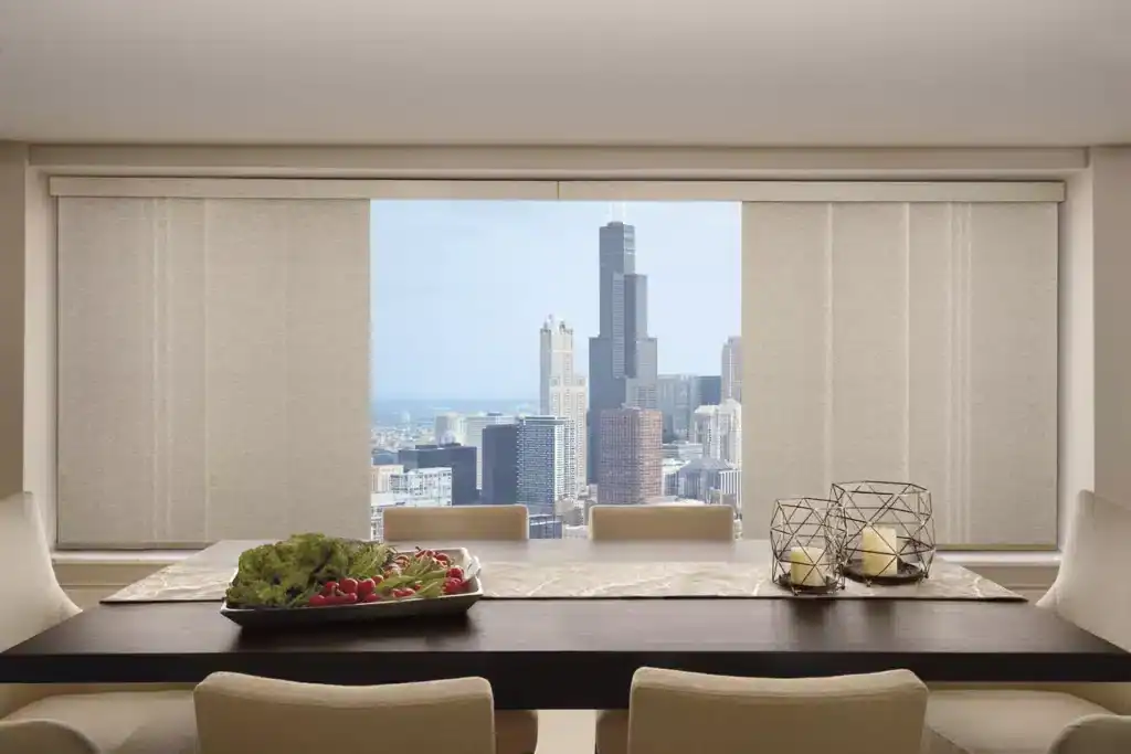 Panoramic view of downtown Chicago from a chic dining room with city buildings and clear daylight through large windows.