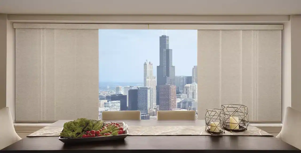 Panoramic view of downtown Chicago from a chic dining room with city buildings and clear daylight through large windows.
