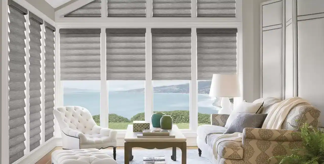 Bright, inviting sunlit room with large windows overlooking the sea, featuring elegant furniture, neutral tones, and stylish window treatments for a relaxing seaside ambiance.