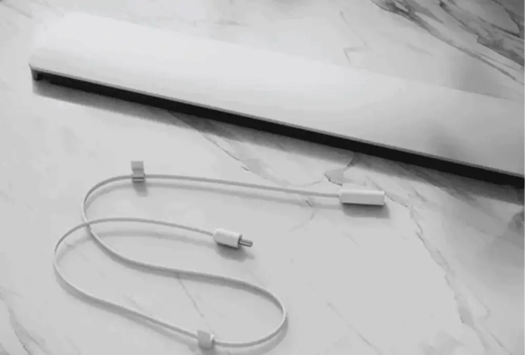 White laptop power cable with inline connector on a marble surface.
