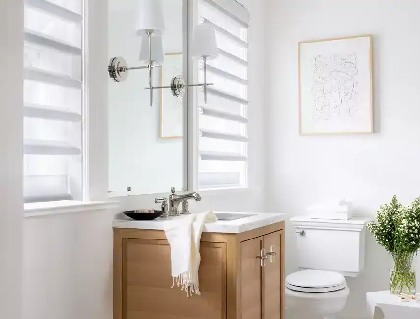 Bright bathroom with wooden vanity, large mirror, white walls, and modern decor elements.