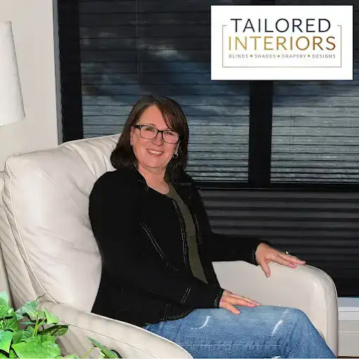 A professional woman sitting comfortably in a modern interior space, showcasing her expertise in tailored interior design solutions.