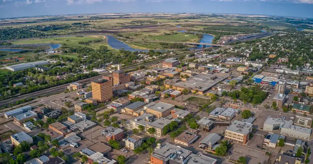 Aerial view of Brandon, Manitoba highlighting downtown buildings, residential areas, and nearby rivers in a vibrant cityscape.