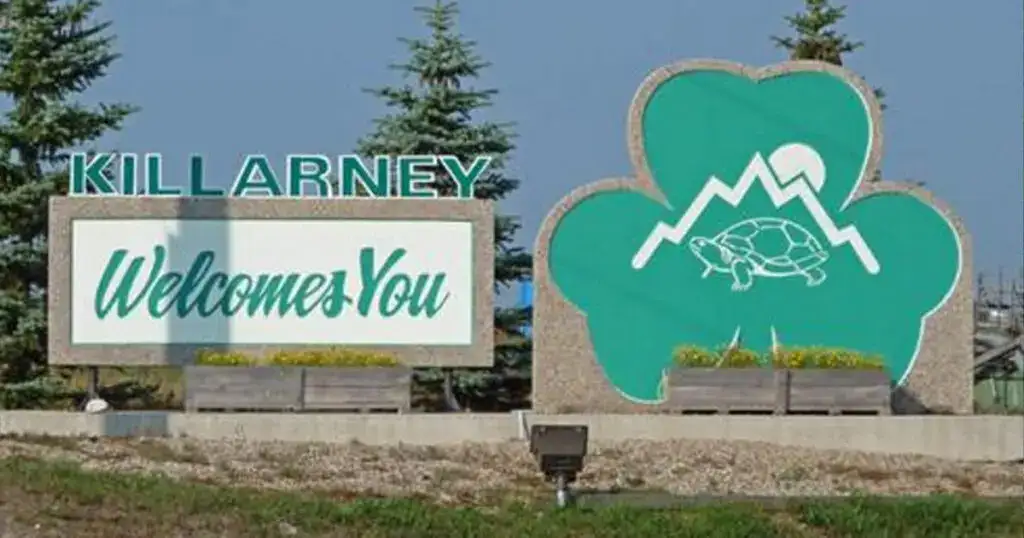 Welcome sign at Killarney, Manitoba featuring mountain, lake, and turtle symbols representing local nature and outdoor activities.