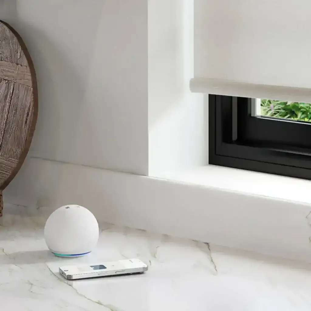 Smart home device with voice assistant on marble windowsill near window.