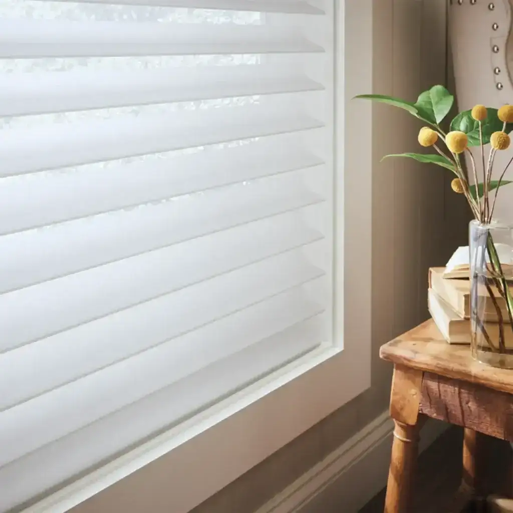 Bright window with white horizontal blinds and a potted plant on a wooden side table.