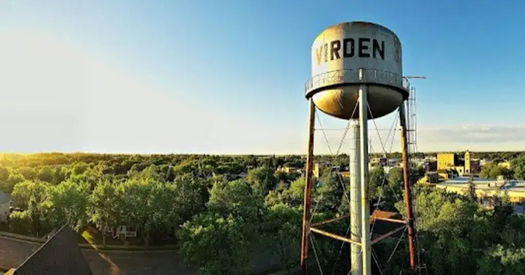 Water tower in Virden, Manitoba with cityscape background.