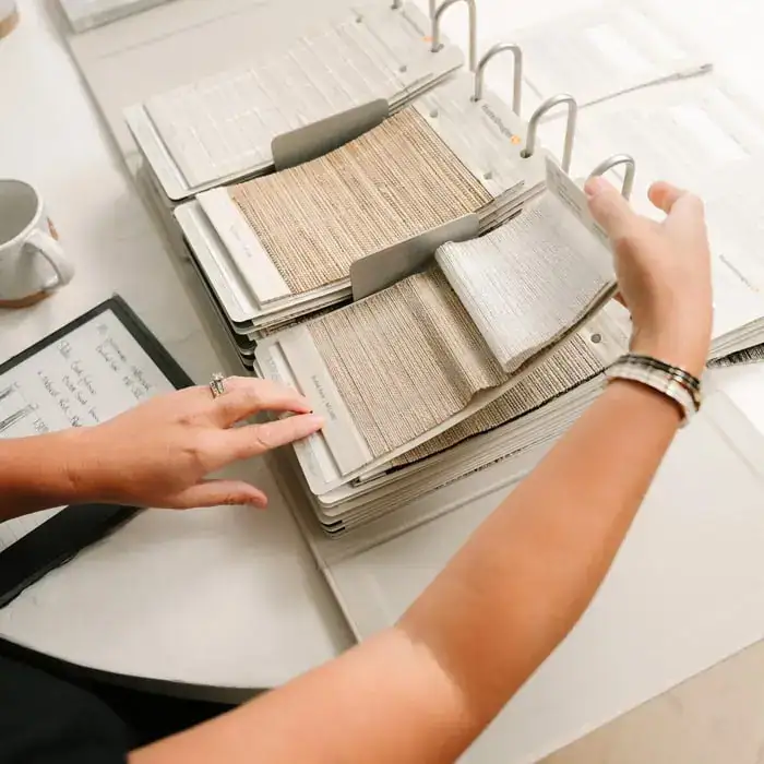 Sample book with fabric swatches displaying different textures, colors, and patterns for interior decor or fashion design.
